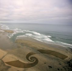 an aerial view of the beach and ocean with two spirals painted on it's sand