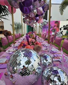 the table is set up for a party with disco ball decorations and pink linens