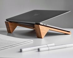 an apple laptop sitting on top of a wooden stand