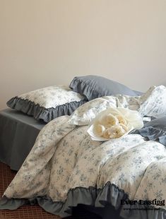 an unmade bed with blue and white bedspread, pillows and flowers on it