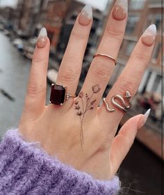 a woman's hand with three different rings on it and one ring has a flower