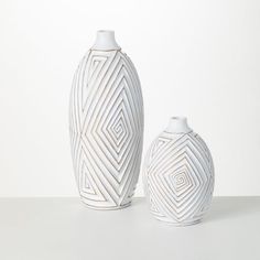 two white vases sitting next to each other on a table