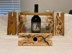 three wine glasses and two bottles are sitting on a bed with wood blocks that have been designed to look like branches