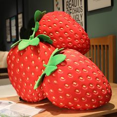 two red strawberries sitting on top of a wooden table next to eachother