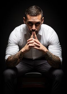 a man sitting on top of a chair with his hands in his mouth