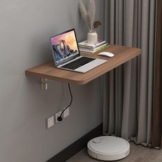 a laptop computer sitting on top of a wooden desk next to a wall mounted speaker