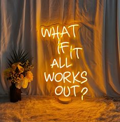 a neon sign that says what if it all works out? next to a vase with flowers