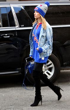 a woman in black boots and a blue jacket is walking down the street with her handbag