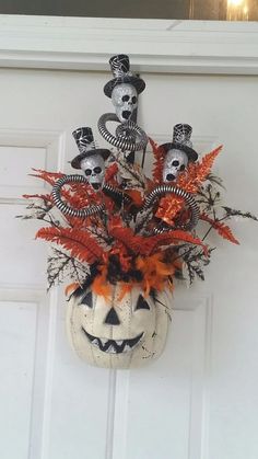 a halloween decoration hanging on the front door with pumpkins and skeleton heads in it