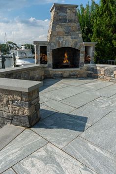 an outdoor fireplace and seating area with boats in the background