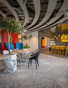 the interior of a modern office with colorful chairs and tables in front of a bar