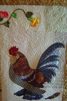 a quilted wall hanging with a rooster on it's side and flowers in the background