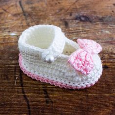 a crocheted baby bootie with a pink bow on the front and bottom