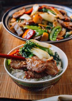 two bowls filled with meat and vegetables on top of rice next to chopsticks