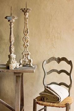 an old chair and table with two candlesticks next to each other on the floor