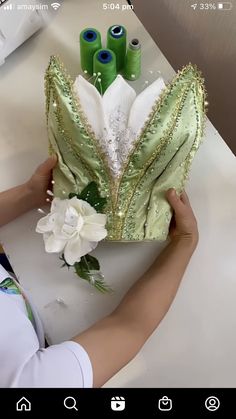 a woman is working on something with green and white flowers in front of her face