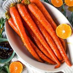 carrots are in a bowl with orange slices on the side