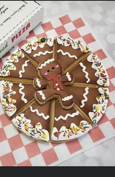 there is a large cookie decorated like a ginger on the table next to a box of pizza