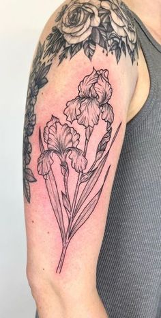 a woman's arm with flowers and leaves tattooed on the back of her shoulder