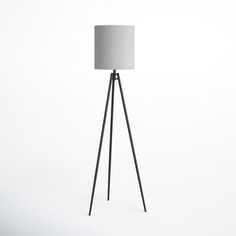 a black tripod floor lamp with a white linen shade on the top and bottom