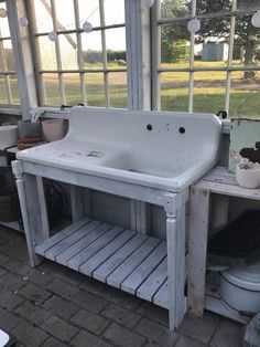 an old white sink sitting in the middle of a room next to a toilet and window