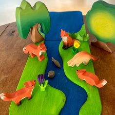 a wooden table topped with toy animals on top of green trays