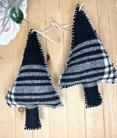 two black and white christmas trees hanging from strings on a wooden floor next to ornaments