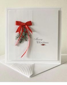 a christmas card with a red bow and holly on the front, sitting on top of a white envelope