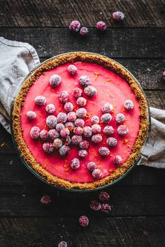 a pie topped with powdered sugar and raspberries on top of a wooden table