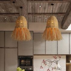 two lamps hanging from the ceiling above a kitchen counter with an oven and toaster