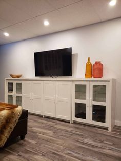 a large flat screen tv sitting on top of a white entertainment center