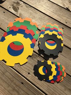 four pieces of paper cut out to look like gears on a wooden table with wood planks in the background