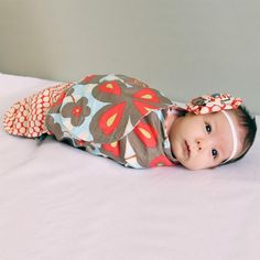 a baby laying on top of a bed wearing a headband