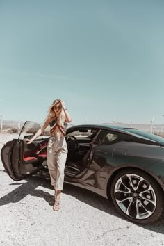 a woman standing next to a black sports car