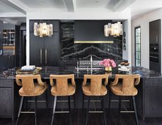 an elegant kitchen with marble counter tops and black cabinetry, along with gold accents