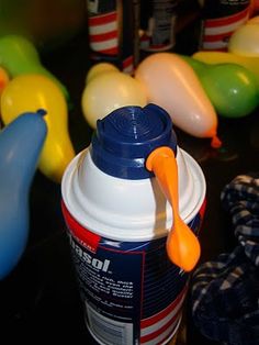 a plastic cup with an orange spoon sticking out of it next to balloons and other toys