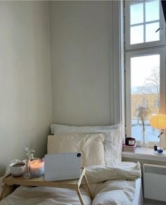 a laptop computer sitting on top of a bed next to a window with a view