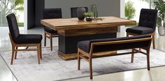 a dining room table with black chairs and a white rug on the floor in front of it