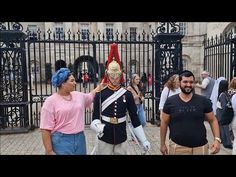 two men in uniform walking past people with blue turbans and pink shirts on