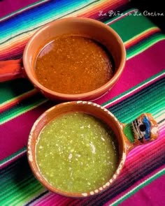 two bowls filled with different colored sauces on top of a colorful table cloth next to each other