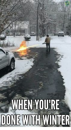 a man is walking down the street in front of a car that has flames coming out of it