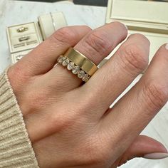 a woman's hand holding a gold ring with three diamonds on it and two other rings in the background