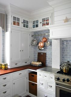 a kitchen with white cabinets and wooden counter tops