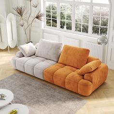 an orange and white couch sitting on top of a wooden floor next to a window