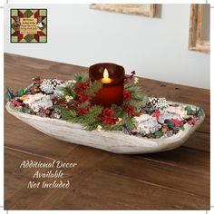 a candle is lit in a boat with pine cones and holly wreaths on it