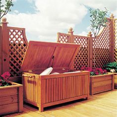 a large wooden box sitting on top of a hard wood floor next to potted plants