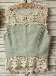 a green top with lace on it hanging from a wooden wall next to a white door