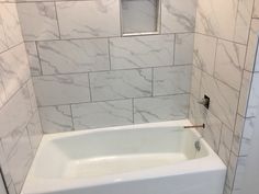 a white bath tub sitting inside of a bathroom next to a tiled wall and floor