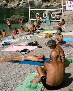 people sitting on the beach with towels around them