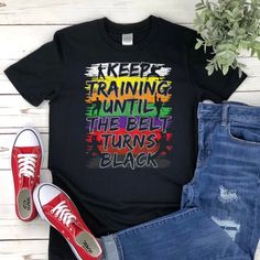 a t - shirt that says keep training until the belt turns black on top of ripped jeans